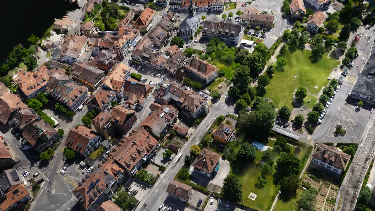 A small town rebuilt by Helios as a Gaussian splat from one drone flight, seen from above at an angle.