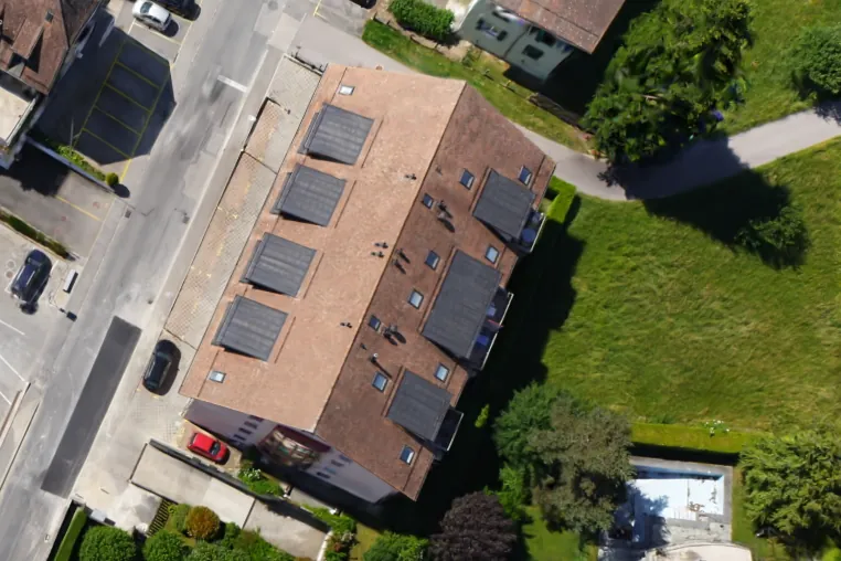 A closer view from the same splat: a roof with solar panels, the street beside it and a garden.